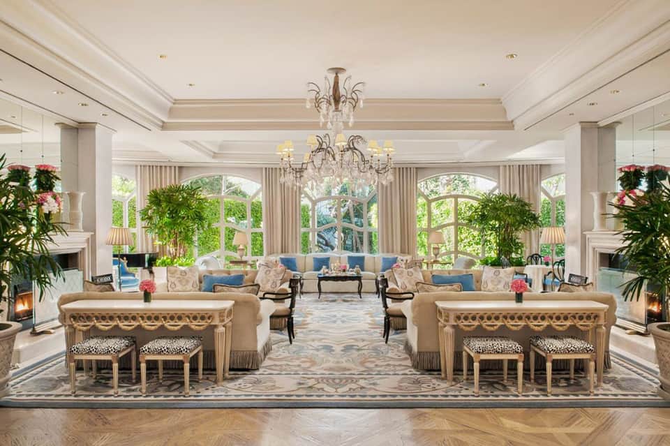Elegant hotel lobby with crystal chandelier, cream columns, blue seating, and large windows