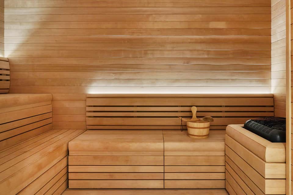 Wooden sauna interior with benches, bucket, and ambient lighting