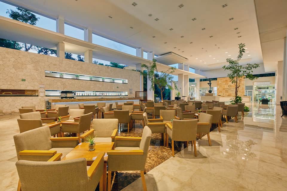 Spacious hotel lounge with comfortable seating, soaring windows, stone walls, and modern decor