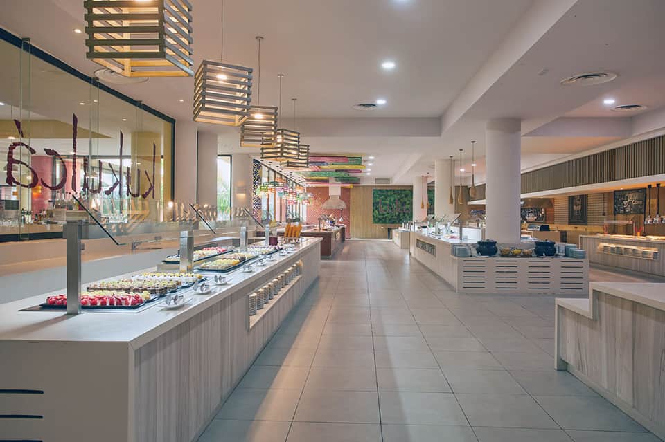 Modern hotel buffet area with multiple food stations, pendant lighting, and colorful decorative artwork