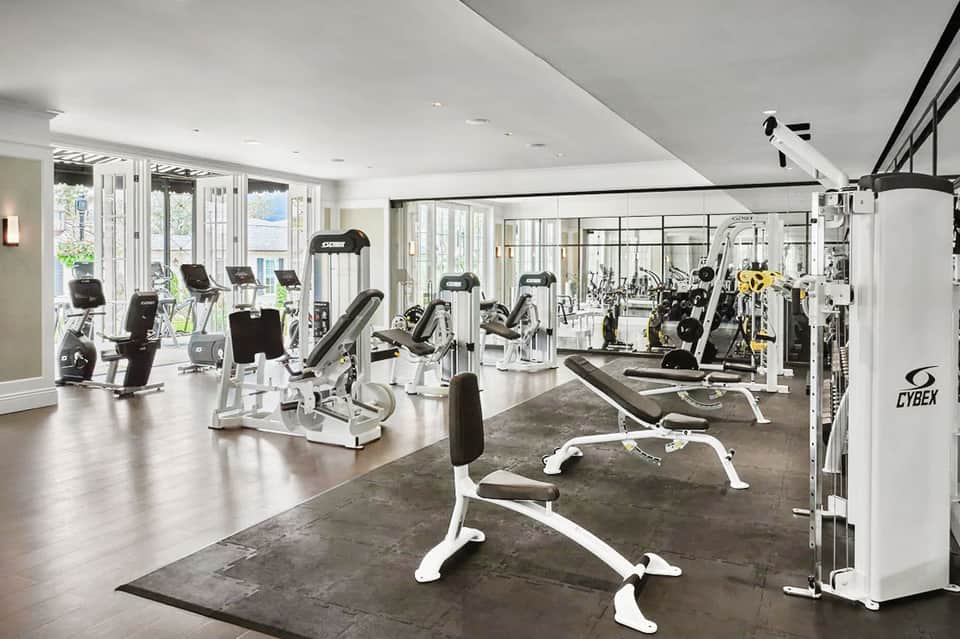 Modern gym with white and black equipment, including stationary bikes, weight machines, and exercise bikes