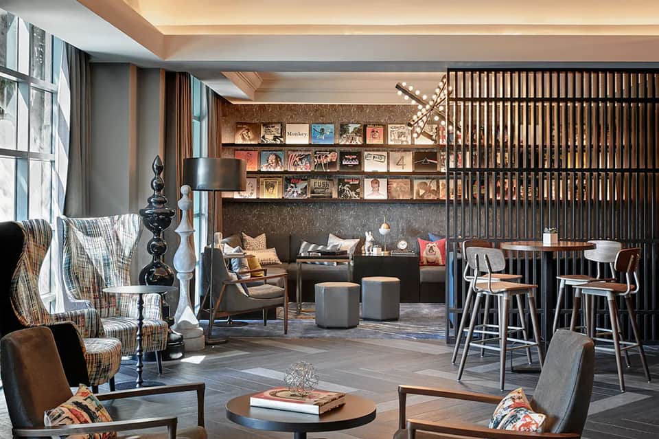 Upscale hotel lounge with modern furniture, shelving, bar seating, and artwork