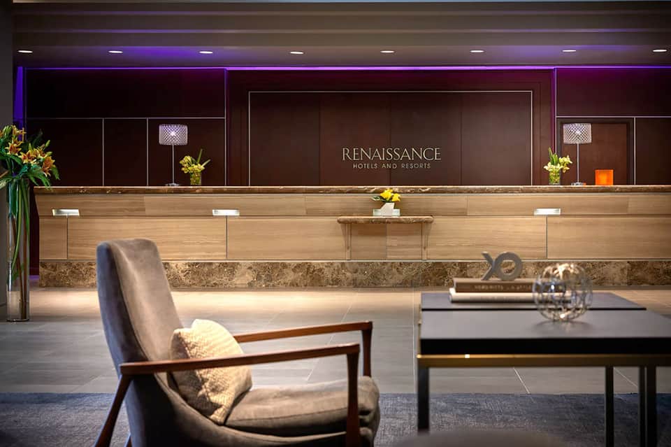 Luxury hotel lobby with Renaissance branding, marble floors, wooden reception desk, and modern ambient lighting