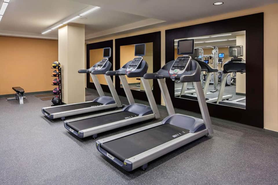 Modern fitness center with multiple treadmills, mirrors, and contemporary equipment setup