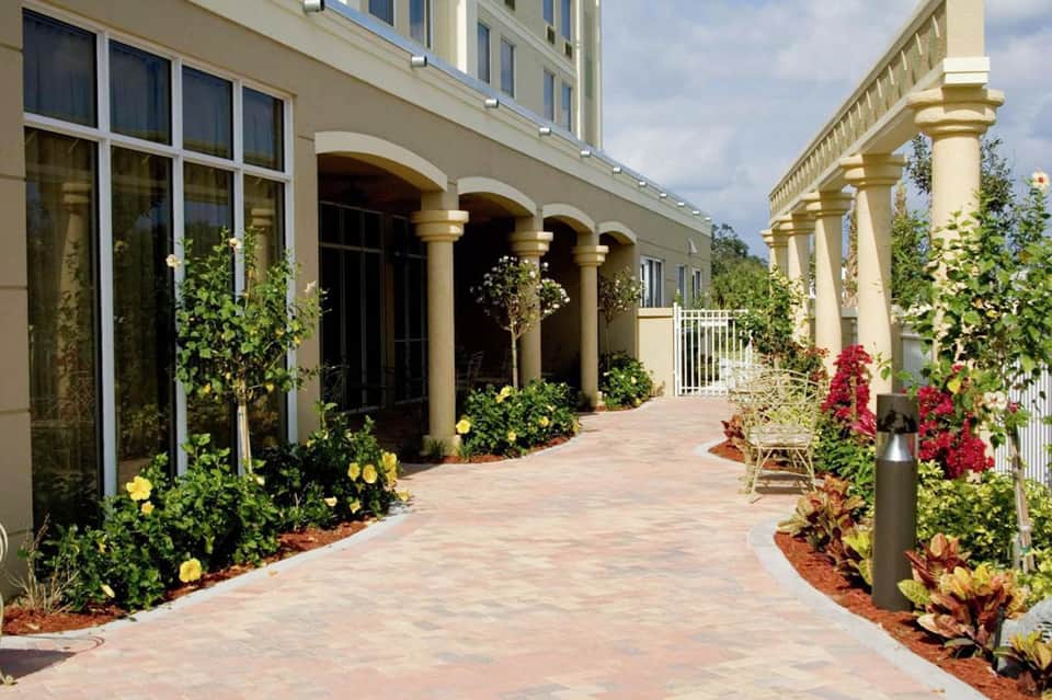 Classical covered colonnade with yellow columns and manicured flowering gardens