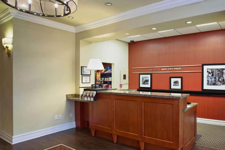 Hotel front desk reception area with coral accent wall and historic West Palm Beach signage