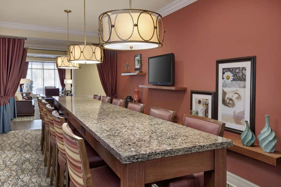 Elegant hotel meeting room with granite table, hanging pendant lights, and coral accent walls