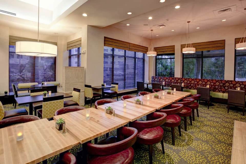 Modern hotel meeting room with long wooden table, burgundy chairs, and floor-to-ceiling windows