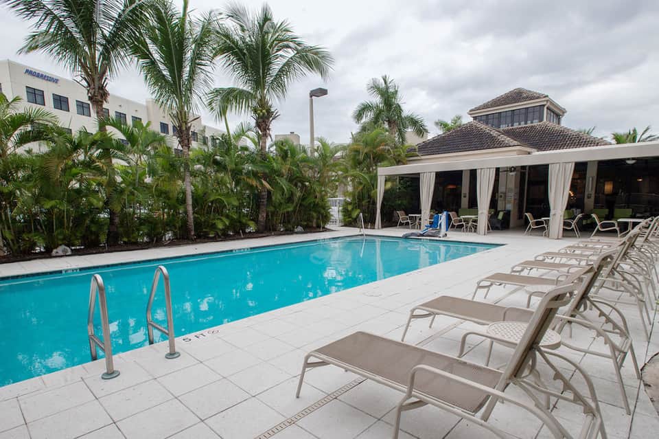 Rectangular pool with covered cabana, lounge chairs, and tropical landscaping