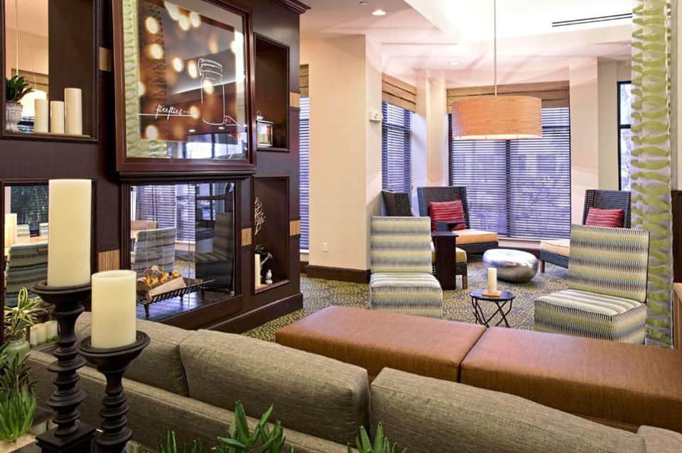 Modern hotel lobby lounge with fireplace, seating areas, striped curtains, and contemporary decor