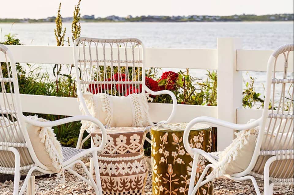 White wicker chairs and potted flowers on waterfront patio overlooking bay