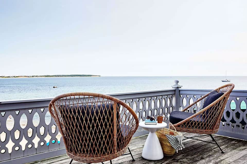 Woven lounge chairs on oceanfront boardwalk with calm bay view and boats