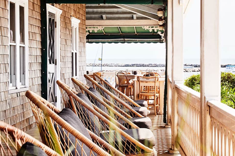 Waterfront deck with woven lounge chairs overlooking bay and wooden railings