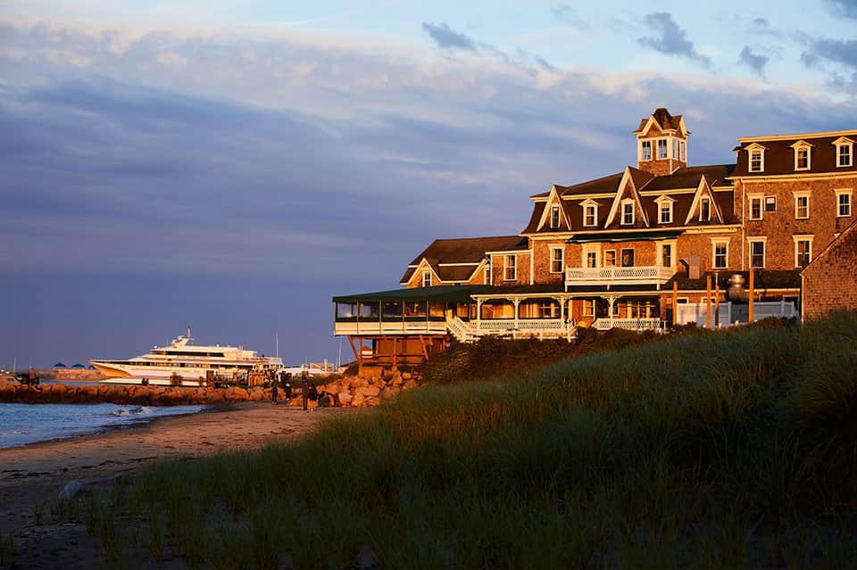 Historic brick mansion on beach at sunset with anchored yacht nearby