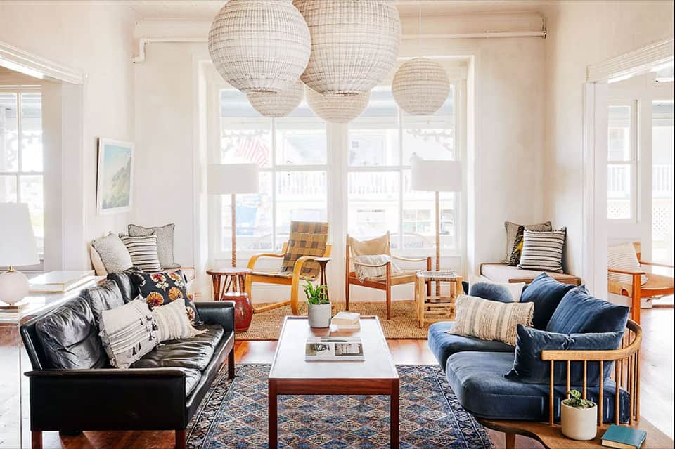 Bright coastal living room with leather sofas, woven pendant lights, and ocean views