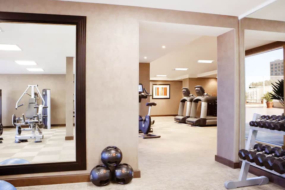 Contemporary fitness center with exercise equipment, mirrors, and neutral beige tones
