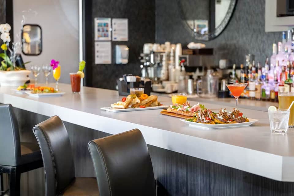 Modern resort bar with white counter, colorful cocktails, appetizers, and full bar setup