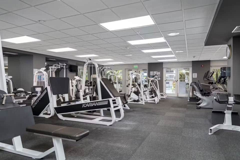 Modern gym facility with white exercise equipment and mirrored walls