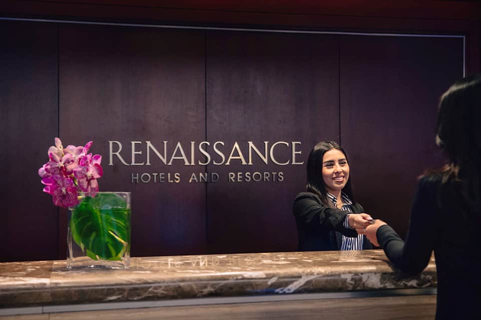 Hotel reception desk with Renaissance Hotels and Resorts branding and smiling staff member