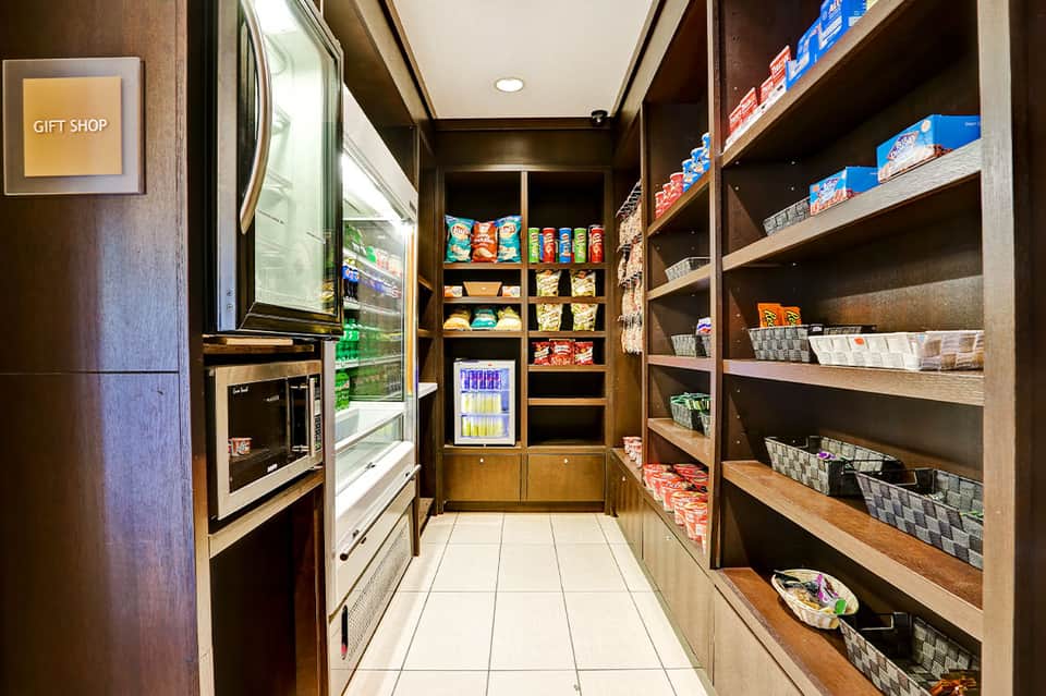 Hotel gift shop interior with refrigerated beverages, snacks, and products on wooden shelves