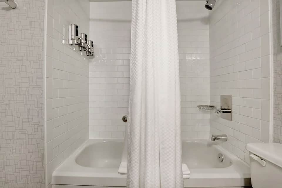 Clean white bathroom with dual sinks, subway tile walls, shower area, and chrome fixtures