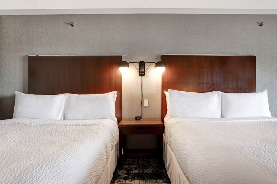 Twin beds with white linens and wooden headboards in hotel room