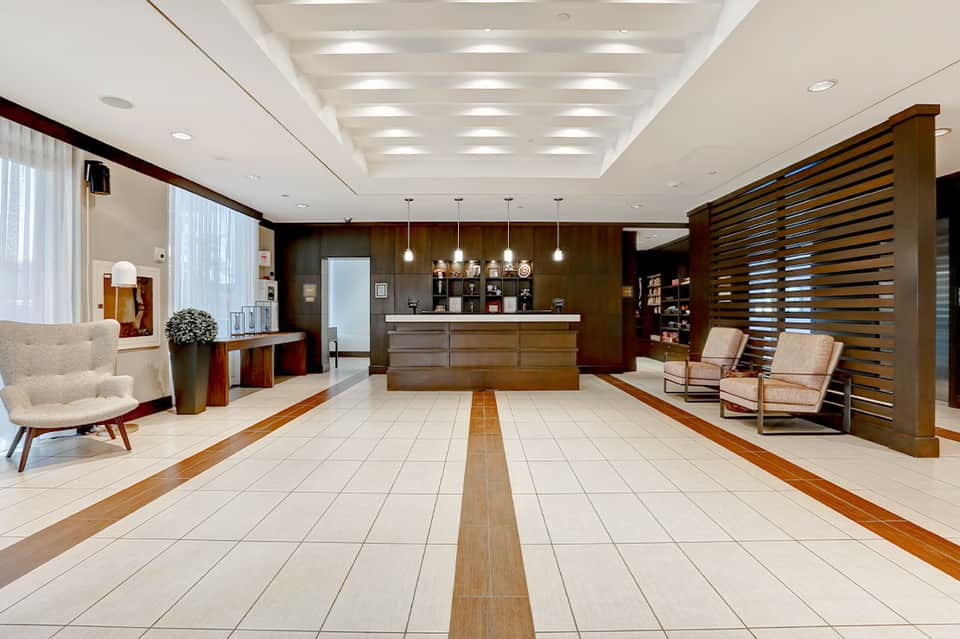 Upscale hotel lobby with wooden accents, marble flooring, reception desk, and contemporary furnishings