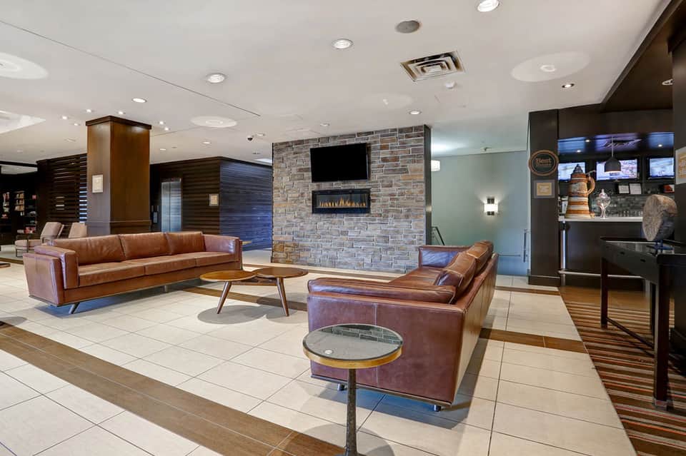 Hotel lobby lounge with leather seating, fireplace, stone accent wall, and modern decor