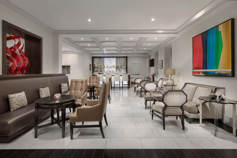 Elegant hotel lounge with coffered ceiling, comfortable seating, bar area, and colorful abstract wall art