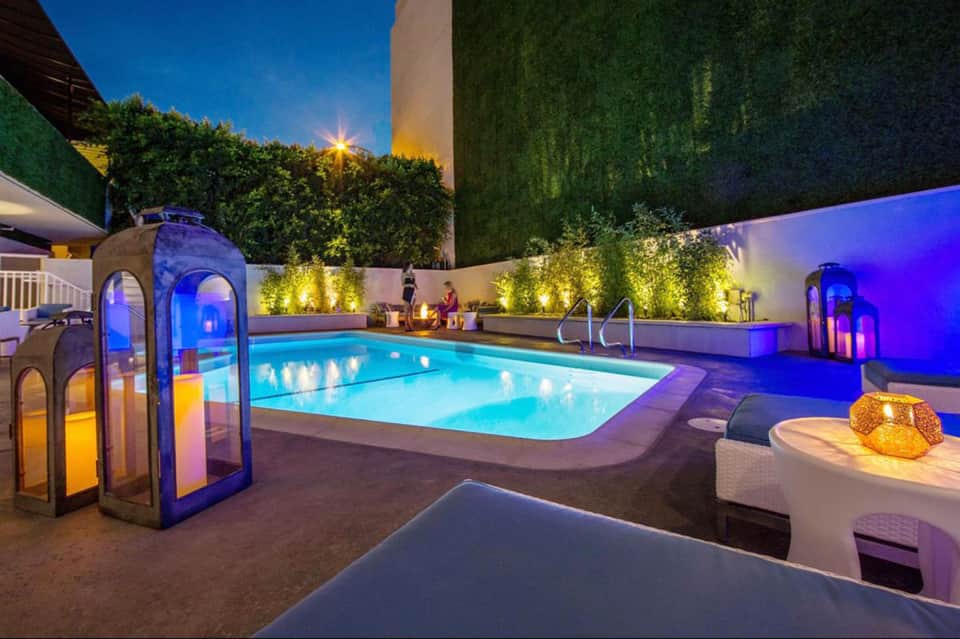Illuminated evening pool surrounded by landscaping and modern architectural structures