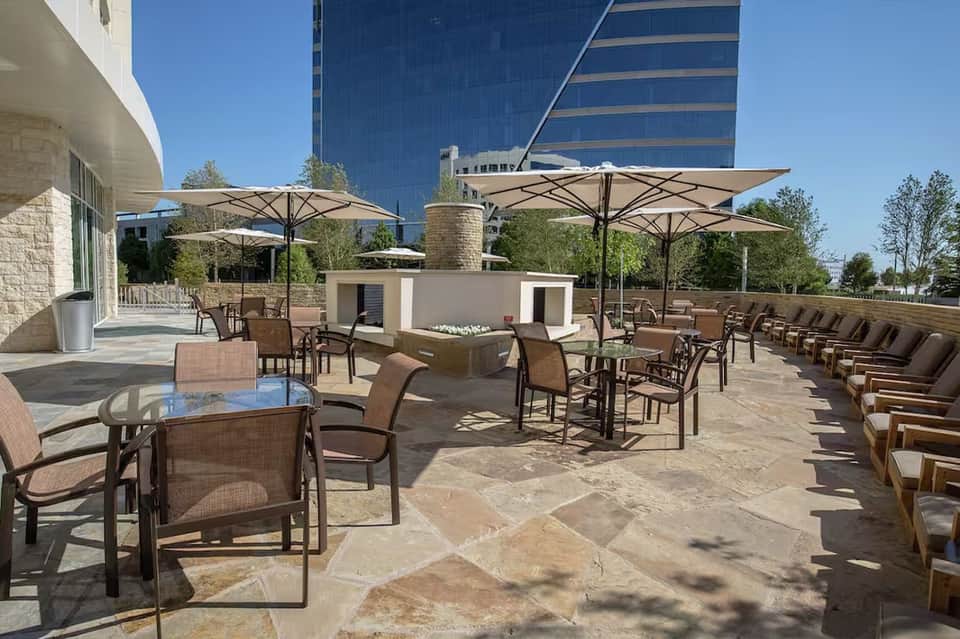Rooftop terrace with umbrella-shaded seating, modern furnishings, and city skyline views