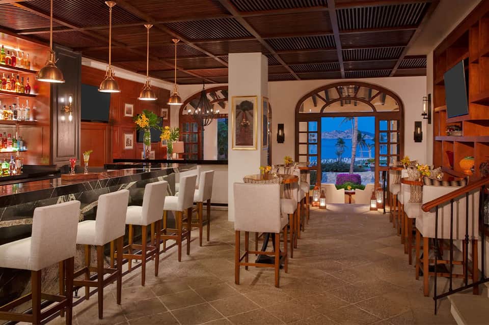 Upscale bar and lounge with wood accents, copper lighting, and ocean view through arched windows