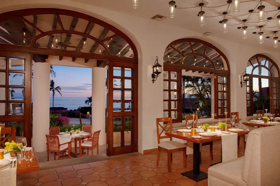 Elegant oceanview dining room with arched wooden doors and sunset vista