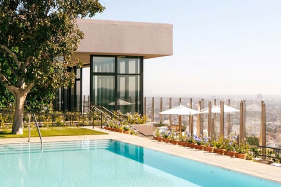 Infinity pool overlooking cityscape with modern glass building and landscaped terrace
