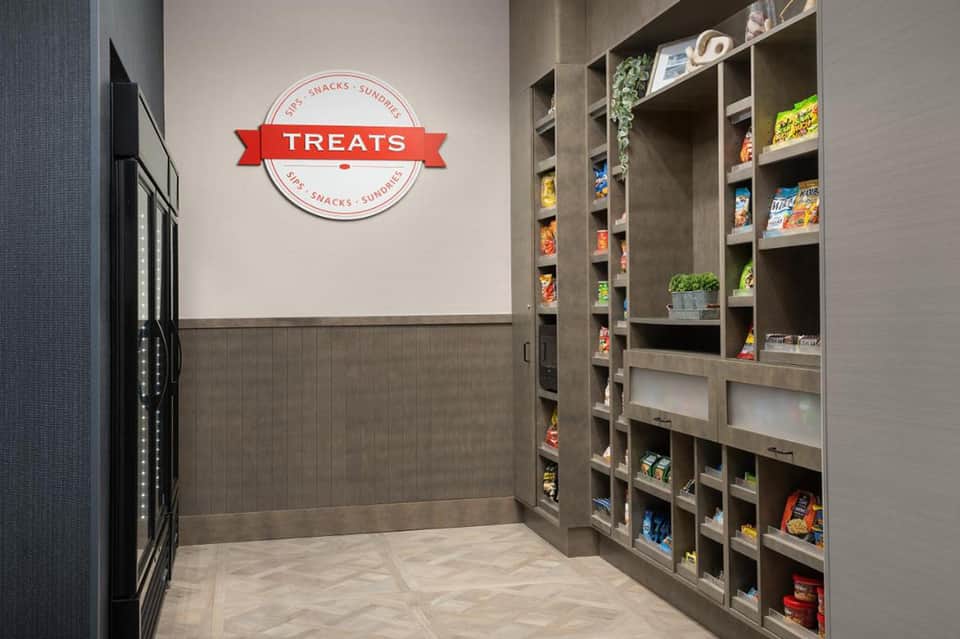 Hotel treats shop with 'TREATS' sign, stocked shelving, and vending machine for snacks and beverages