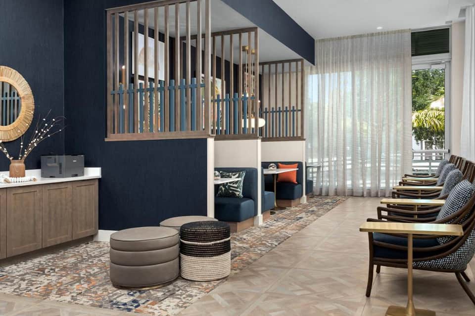 Modern hotel kids club with navy walls, wooden crib, play nook, and ocean-view windows