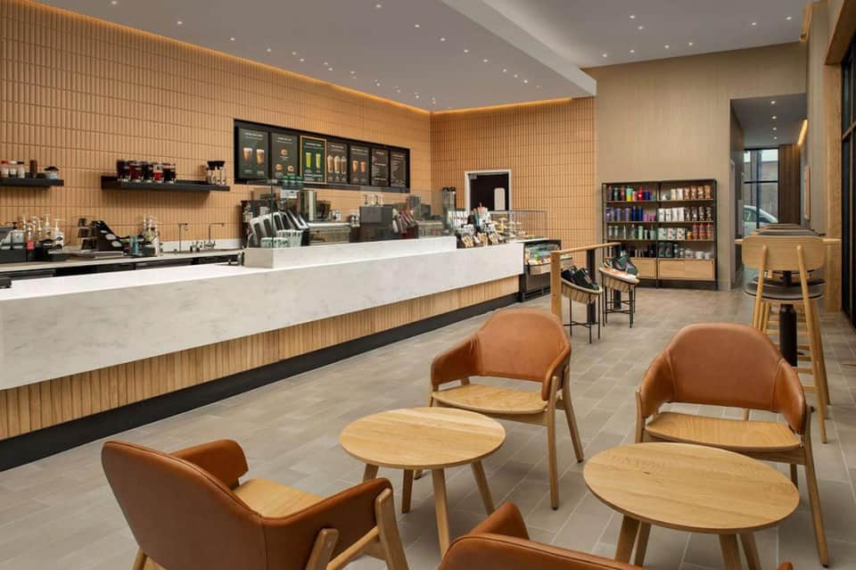 Bright café space with wood-paneled walls, white counter, brown leather chairs, and retail shelving