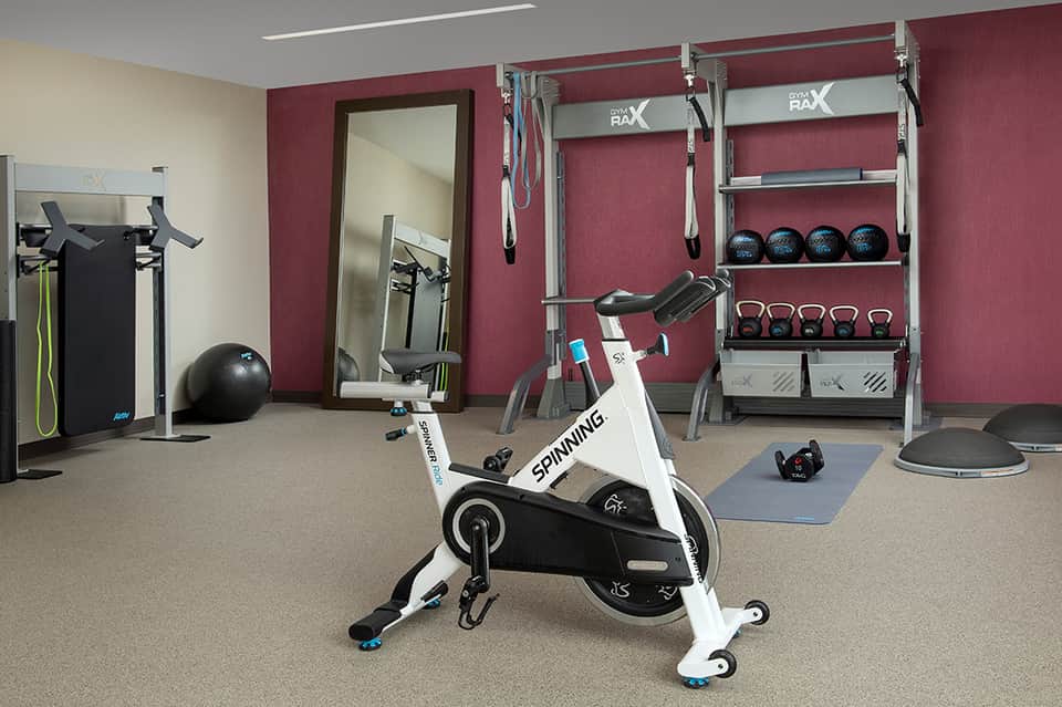 Modern fitness center with cardio equipment, weights, and burgundy accent wall