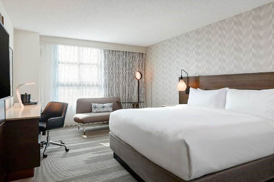 Modern hotel room with king bed, desk, sofa, and contemporary furnishings