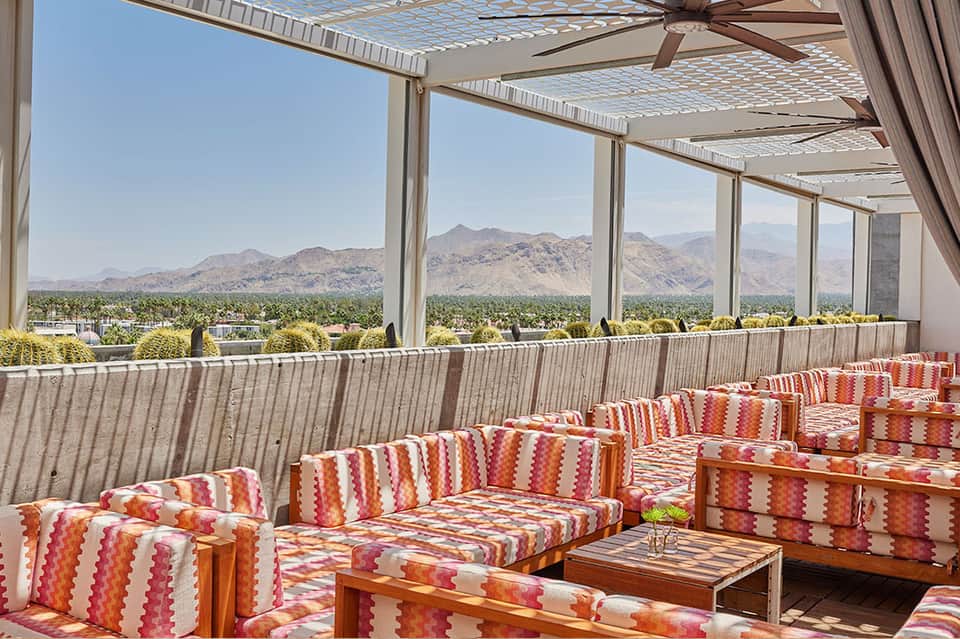 Mountain view lounge with colorful striped seating, pergola ceiling, and scenic alpine backdrop