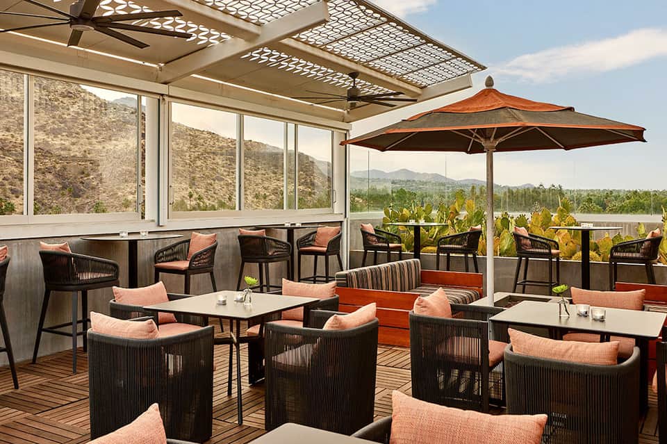 Modern resort terrace with mountain views, lounge seating, and umbrellas