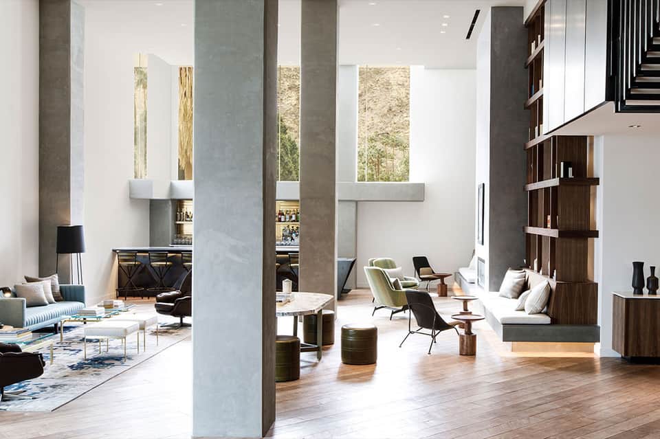 Modern hotel lobby with high ceilings, concrete columns, and contemporary furniture arrangement