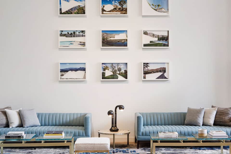 Hotel lobby with light blue velvet sofas and wall gallery of nine framed landscape photographs