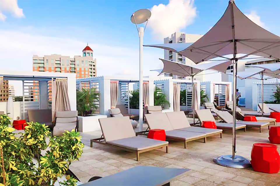 Rooftop pool deck with loungers, umbrellas, and city skyline views