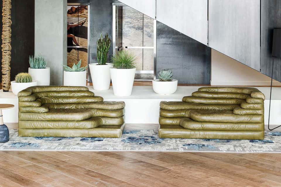 Contemporary interior with sculptural olive-green leather seating and white potted plants