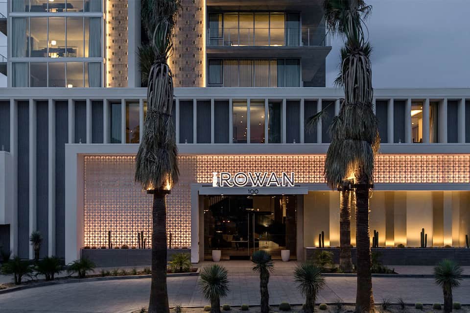 Modern hotel storefront entrance with illuminated signage reading 'ROWAN' and palm trees