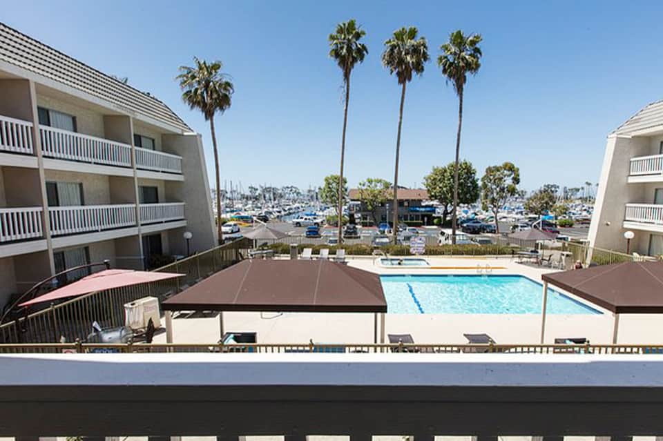 Resort pool with covered cabana, palm trees, and marina view in background