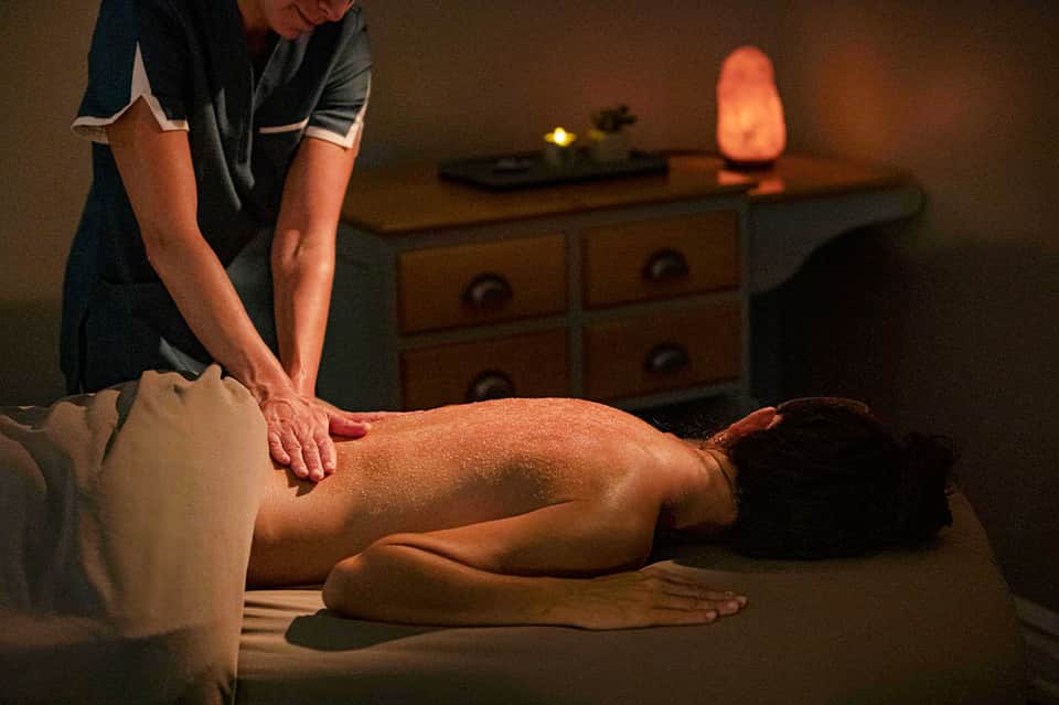 Professional massage therapist providing treatment in candlelit spa room