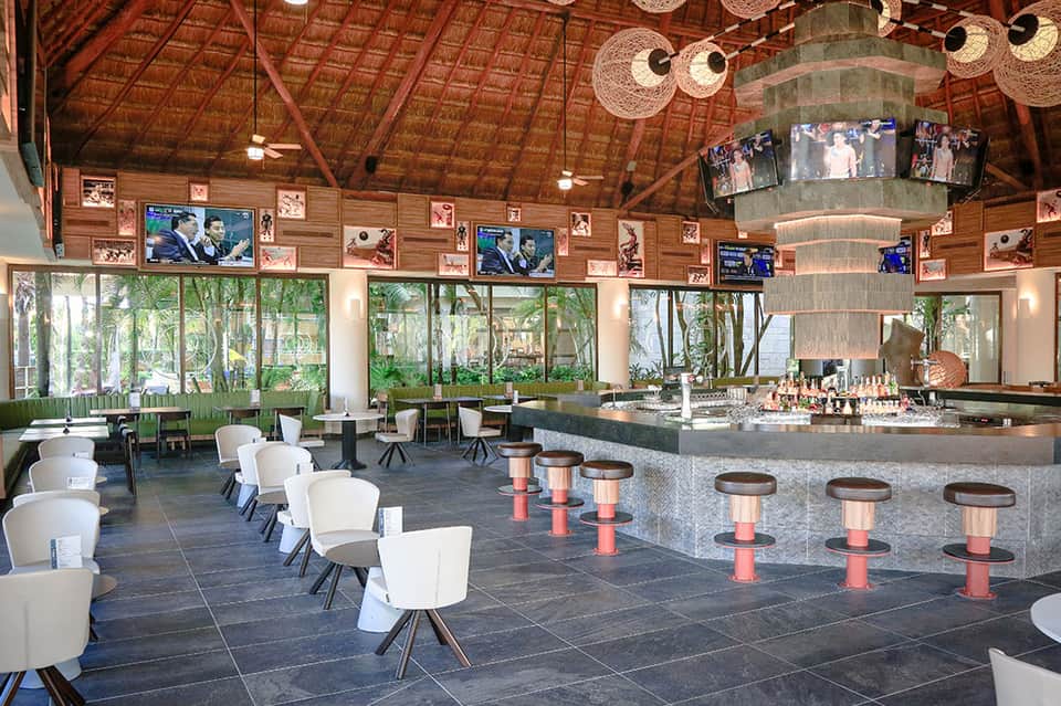 Modern resort bar lounge with stone counters, wooden ceiling, and forest views