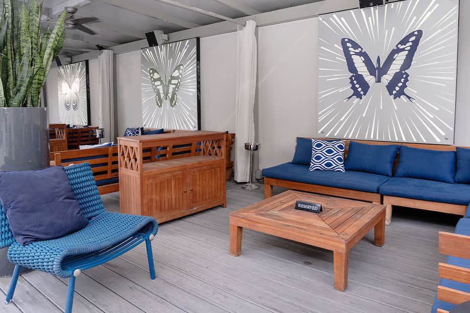 Modern lounge area with wooden furniture, blue cushions, and large butterfly artwork on illuminated walls